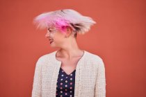 Безтурботний альтернативний жіночий кидання фарбованого короткого волосся на помаранчеву стіну в міській місцевості — стокове фото