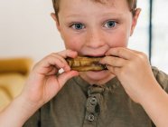 Nahaufnahme eines emotionslosen Kindes, das beim Mittagessen zu Hause appetitliche Schweinerippchen isst und nach unten schaut — Stockfoto