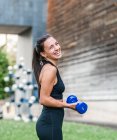 Atleta determinata che fa esercizio con i manubri durante l'allenamento di fitness sulla strada della città in estate — Foto stock