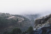 Vista panoramica di Pedriza con nebbia che si diffonde tra la catena montuosa di Guadarrama e massi con conifere all'alba in Spagna — Foto stock