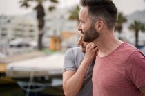 Зміст пари гомосексуальних чоловіків у футболках, що захоплюються, дивлячись у гавань — стокове фото