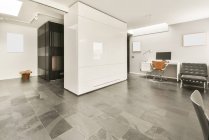 Style loft minimaliste intérieur de hall spacieux moderne avec des murs blancs et un sol en marbre meublé avec des fauteuils et décoré avec des planches de maquette vierges — Photo de stock