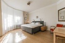 Комфортне ліжко і дерев'яні тумбочки розміщені в просторій спальні в сучасній квартирі — стокове фото