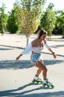 Вид збоку на жінку в роликових лопатях, що показують трюк на дорозі в місті влітку — стокове фото