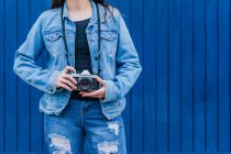 Crop unrecognizable female photographer in denim jacket and jeans standing with vintage photo camera — Stock Photo