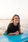 Entzückte Surferin auf SUP-Board liegend und an sonnigen Tagen auf ruhigem Wasser treibend — Stockfoto