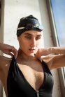 Portrait of beautiful young swimmer woman sit down with black swimwear hat and swimming goggles — Stock Photo
