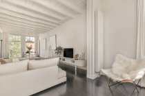 Просторная белая гостиная с удобным диваном и стулом в современном доме — стоковое фото