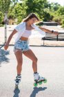 Joven hembra en patines que muestra acrobacias en carretera en la ciudad en verano - foto de stock