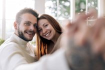 Homem barbudo alegre com mulher sincera amada tomando auto retrato enquanto olha para a câmera em casa — Fotografia de Stock