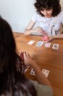 Зверху приємна ЛГБТ-пара жінок, які сидять за столом і грають в карти, коли розважаються вдома. — стокове фото