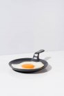 Delicioso huevo frito en sartén negra servido en la mesa sobre fondo blanco en el estudio - foto de stock