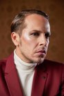 Serious pensive adult male theater artist with makeup and in elegant outfit looking away while thinking over decision — Stock Photo