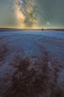 Silhouette of explorer standing in dry salt lagoon on background of starry sky with glowing Milky Way at night — Stock Photo