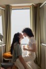 Seitenansicht des Inhalts LGBT-Paar verliebte Frauen auf dem heimischen Sofa und schauen einander mit Liebe an — Stockfoto