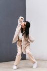 Full length creative female dancer in white clothes dancing in city street during performance touching head with hand — Stock Photo