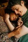 De cima de mulher negra amorosa com os olhos fechados sentados nos joelhos do homem enquanto abraça em casa — Fotografia de Stock
