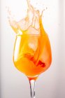 Cocktail arancio rinfrescante spruzzando in calice di vetro lucido su sfondo grigio in studio — Foto stock