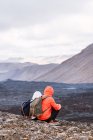 Погляд на анонімних мандрівників у зовнішній білизні, що споглядають лаву Фаградальсфджалла з гори під хмарним небом в Ісландії. — стокове фото
