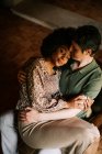 From above of loving black woman sitting on knees of man while embracing at home — Stock Photo