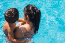 Blick von oben auf unkenntliche Mutter mit Sohn, die an einem sonnigen Sommertag im Schwimmbad steht — Stockfoto