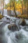 Vista panorâmica do monte com cascatas e rio com fluidos de água espumosos sobre pedras entre árvores de outono em Lozoya, Madri, Espanha. — Fotografia de Stock