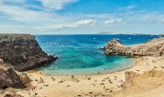 Drone vista sulla spiaggia sabbiosa con turisti situati vicino al mare calmo con acqua turchese pulita nella soleggiata giornata estiva a Fuerteventura, Spagna — Foto stock