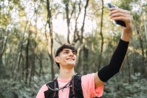 Conteúdo caminhante masculino com mochila tomando selfie enquanto viaja — Fotografia de Stock