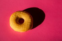 Вид сверху одного классического пончика без обложки на розовом фоне — стоковое фото