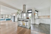 Interior design moderno con isola cucina con bancone e sgabelli sotto il cofano in spazioso appartamento open space in stile loft — Foto stock