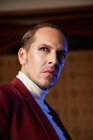 Classy adult male theater artist in burgundy jacket and with makeup looking away with arrogance — Stock Photo