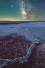 Spectacular scenery of glowing stars of Milky Way in night sky over dry salt lagoon in long exposure — Stock Photo