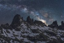 Spettacolare veduta della galassia in cielo con gas interstellare sul maestoso monte grezzo con neve in serata — Foto stock