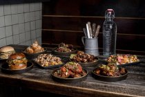 Table en bois servie avec hamburgers appétissants et ailes de poulet au restaurant de street food — Photo de stock