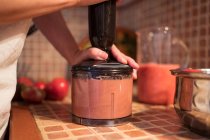 Cultive a dona de casa anônima misturando tomates no liquidificador enquanto prepara o molho marinara na cozinha em casa — Fotografia de Stock