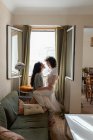 Side view of content ЛГБТ пара женщин обнимаются на диване дома и смотрят друг на друга с любовью — стоковое фото