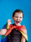 Carino bambino felice con bendaggio multicolore sul collo e polso in piedi sullo sfondo blu e guardando la fotocamera — Foto stock