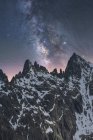 Spettacolare veduta della galassia in cielo con gas interstellare sul maestoso monte grezzo con neve in serata — Foto stock