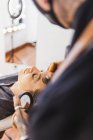Anonymous Man smearing foundation of face of blond woman during work in professional makeup studio — Stock Photo