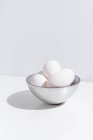 Bowl with fresh chicken eggs placed on table on white background in studio — Stock Photo