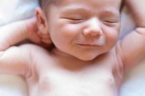Vista superior de lindo pequeño adorable bebé recién nacido desnudo durmiendo acostado en la cama suave en casa - foto de stock