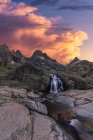 Vue panoramique de la Sierra de Gredos avec cascade et étang avec des fluides d'eau mousseux sous un ciel nuageux au coucher du soleil — Photo de stock