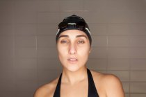 Portrait of beautiful young swimmer woman with black swimwear hat and swimming goggles — Stock Photo