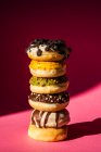 Tower of donuts of different colors and flavors on pink background — Stock Photo