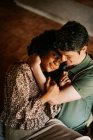 From above of loving black woman sitting on knees of man while embracing at home — Stock Photo