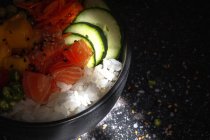 Angolo alto di punta asiatica con salmone e riso con verdure assortite servite in ciotola sul tavolo nel ristorante — Foto stock