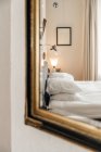 Intérieur de la chambre moderne avec lit doux avec coussins réfléchissant dans le miroir accroché au mur — Photo de stock