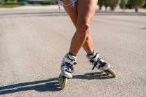 Обрезанная неузнаваемая женщина в роликах показывает трюк на дороге в городе летом — стоковое фото