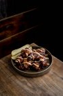 Desde arriba de deliciosas alitas de pollo a la parrilla en salsa barbacoa servida con pepinos en plato sobre mesa de madera en restaurante - foto de stock