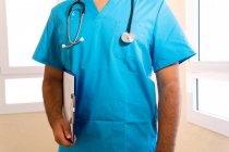Gesichtsloser Arzt in blauer Uniform mit Klemmbrett und Phonendoskop im Krankenhaus — Stockfoto